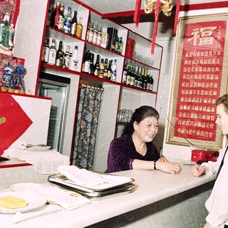 Small restaurant kitchen with woman serving customer.