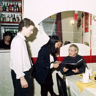 People dining indoors, waiter taking order.
