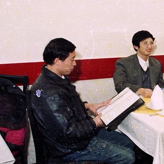 Four men dining together indoors with traditional koi art.