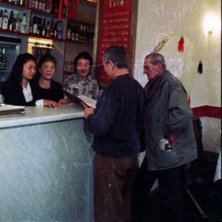 People ordering drinks at a bar with Asian decor.