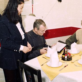 Three people reviewing menus at a restaurant table.