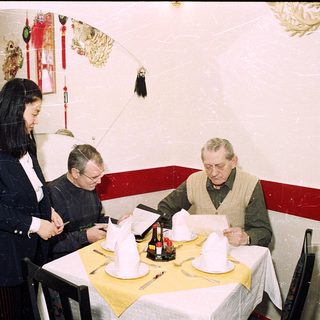 Three people reviewing menus at a restaurant table.