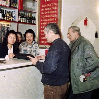 People interacting at a small bar or liquor shop.