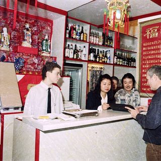People interacting at a small bar or liquor shop.