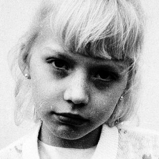Young girl in vintage dress, serious expression.