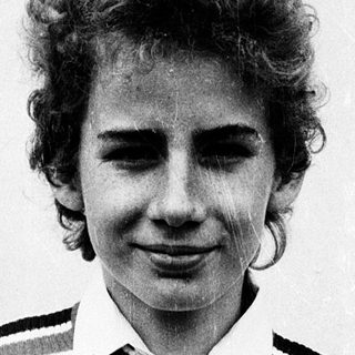 Young person wearing striped sweater, smiling slightly.