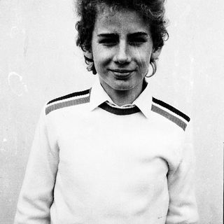 Young person wearing striped sweater, smiling slightly.