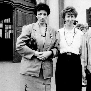 Four women posing together outdoors in formal attire.
