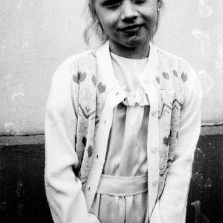 Young girl with blonde hair in vintage dress.