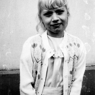 Young girl with blonde hair in vintage dress.