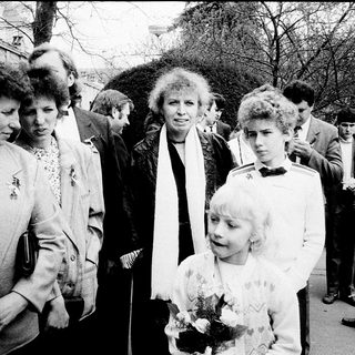 Group of people at outdoor event, including woman holding flowers.