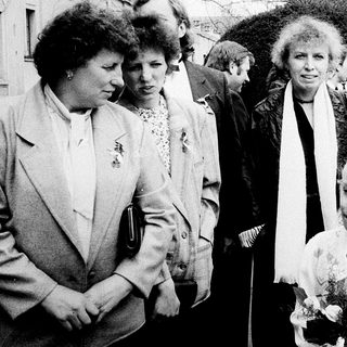 Group of people at outdoor event, including woman holding flowers.