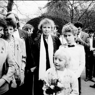 Group of people at outdoor event, including woman holding flowers.