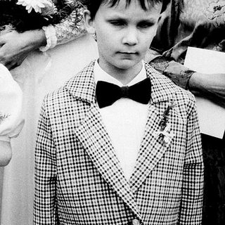 Two children in formal attire at a ceremony.