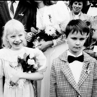 Two children in formal attire at a ceremony.