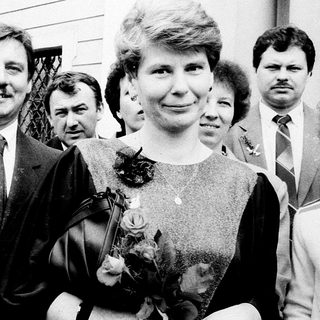 Formal group portrait with man in suit holding flower bouquet.