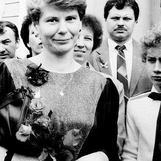 Formal group portrait with man in suit holding flower bouquet.