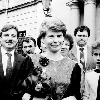 Formal group portrait with man in suit holding flower bouquet.