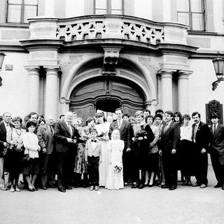 Group wedding photo outside grand historic building.