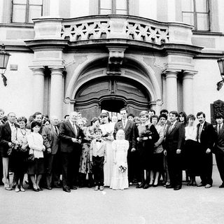 Group wedding photo outside grand historic building.