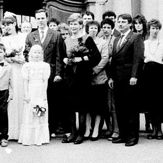 Group wedding photo outside grand historic building.