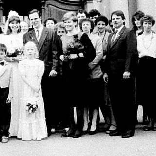 Wedding group photo outside grand building.