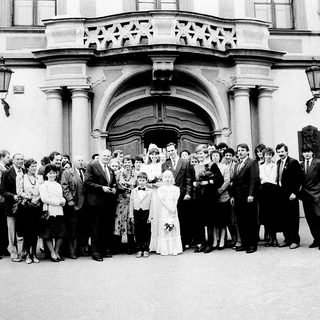 Wedding group photo outside grand building.