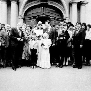 Wedding group photo outside grand building.
