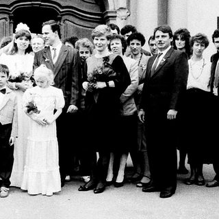 Wedding group photo outside grand building.