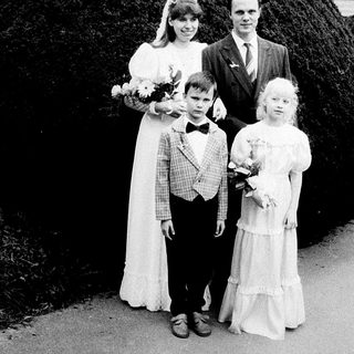 Family wedding photo with bride, groom, and two children.