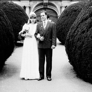 Couple posing in wedding attire outside grand building.