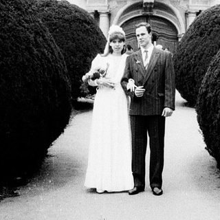 Couple posing in wedding attire outside grand building.