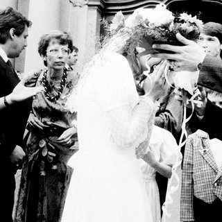 Newlywed couple greeted with confetti outside church.