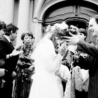 Newlywed couple greeted with confetti outside church.