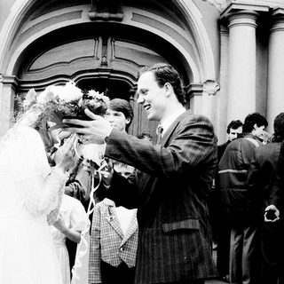 Newlywed couple greeted with confetti outside church.