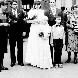 Wedding ceremony with bride, groom, children, and family outside.