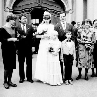 Wedding ceremony with bride, groom, children, and family outside.