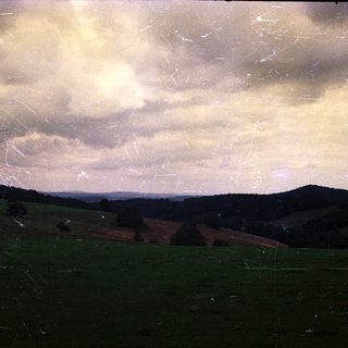 Misty landscape with rolling hills and cloudy sky.
