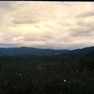 Rural landscape with distant mountains and cloudy sky.