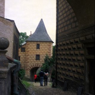 Medieval-style courtyard with stone buildings and arched entrance.