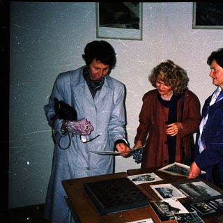 Three individuals examining historical artifacts and documents.