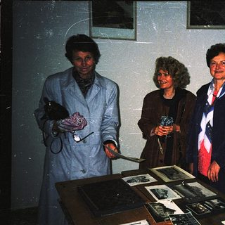 Three women examining historical photographs indoors.