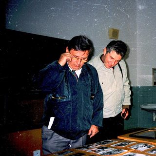 Men examining historical photographs indoors.