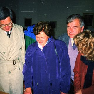 Four people walking indoors during nighttime event.