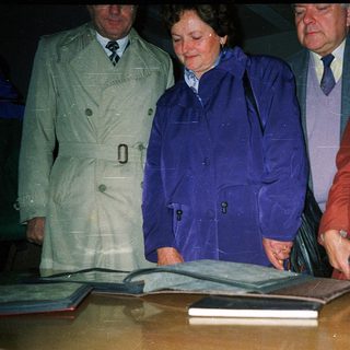 Four individuals signing a large book together.