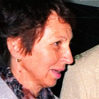 Two people in formal attire examining a handkerchief indoors.