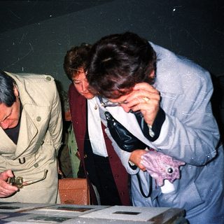 Three people examining historical documents closely.