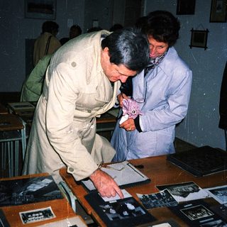 Two men examining vintage photographs in a museum display.