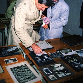Two men examining vintage photographs in a museum display.