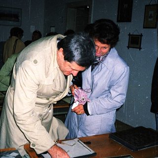 Two men examining vintage photographs in a museum display.